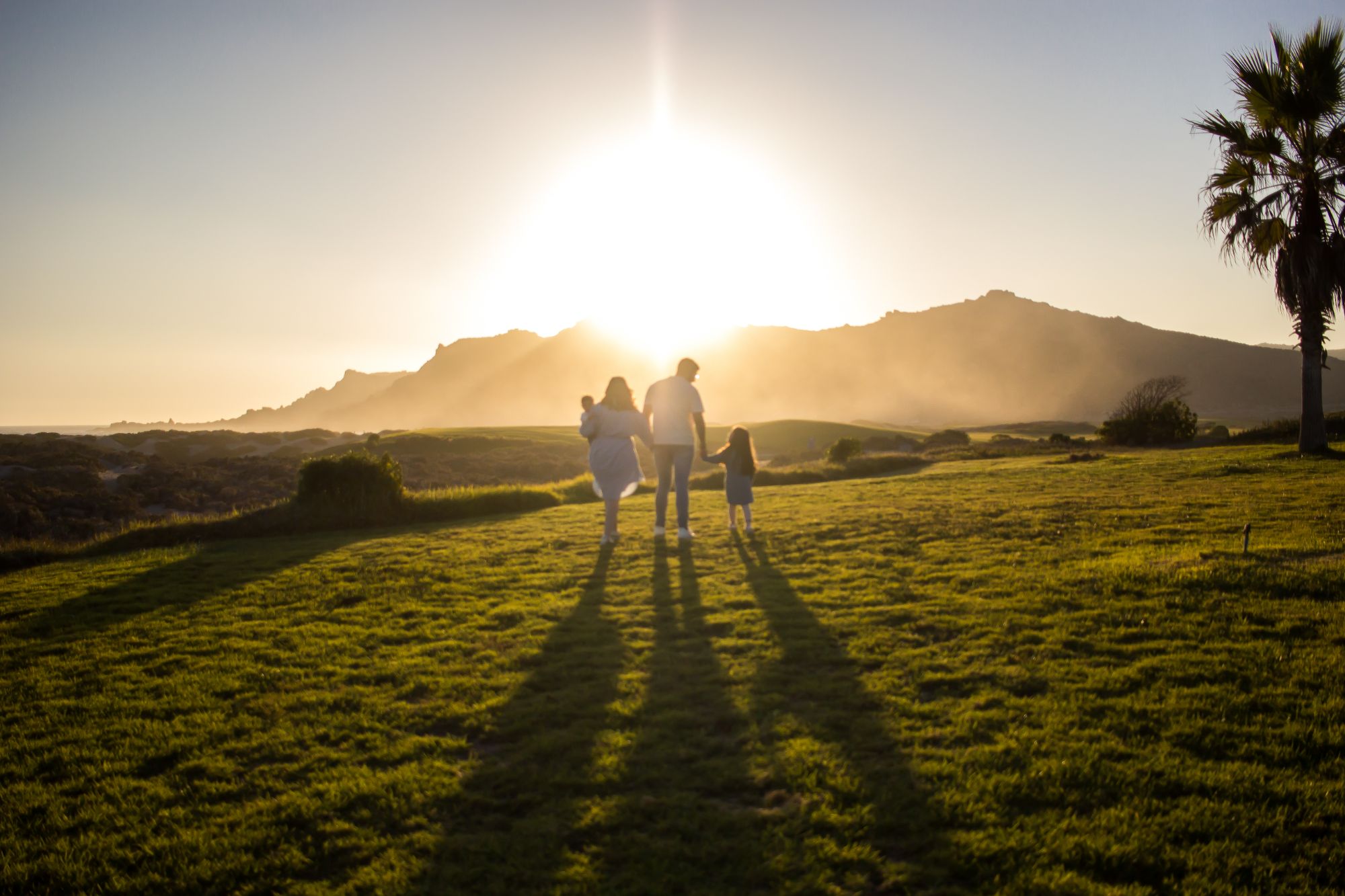 Una familia camina tomada de la mano hacia el atardecer